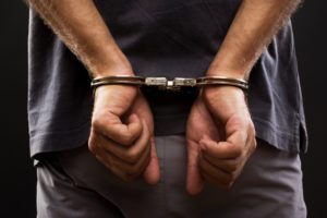 arrested man with hands cuffed behind back