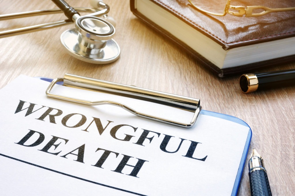 A desk with a stethoscope, a notebook, some pens, and a clipboard with the words “Wrongful Death” written on a piece of paper.